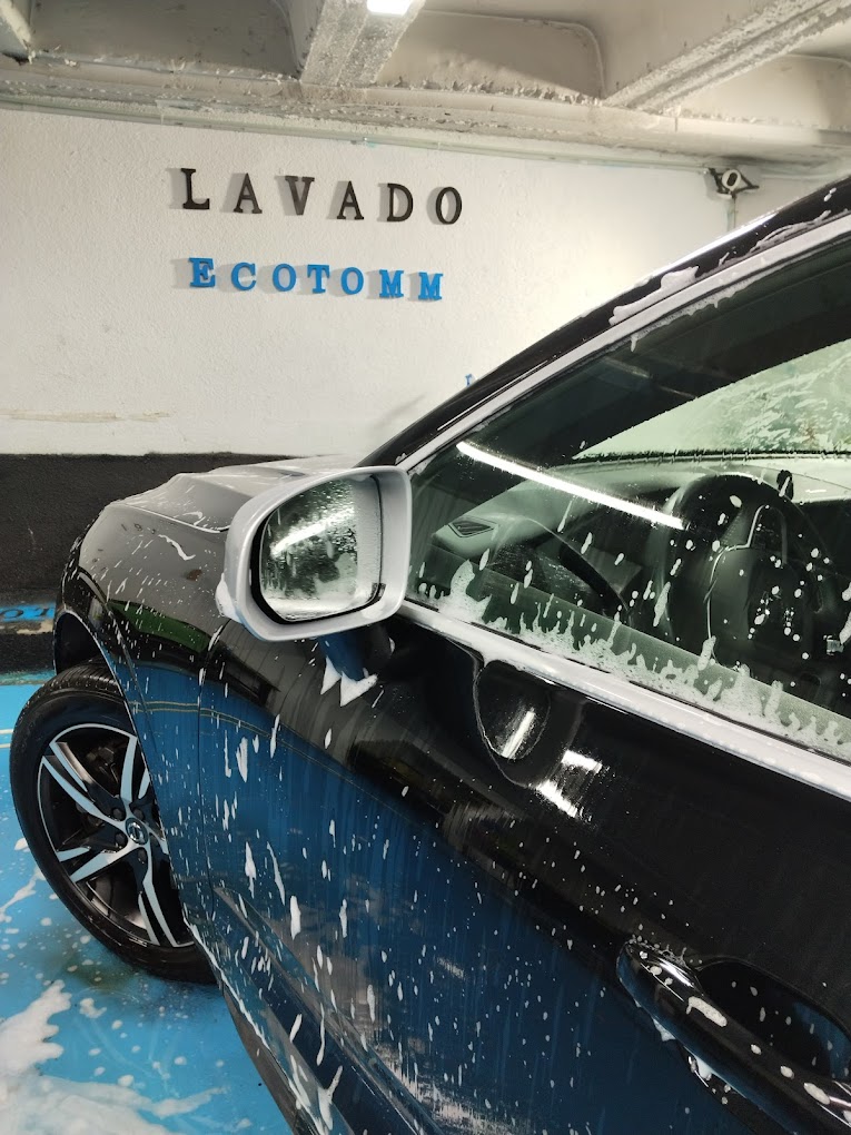 Vista general de la zona de lavado con coche y señal de productos ecológicos/biodegradables. Lavado de vehículos sostenible